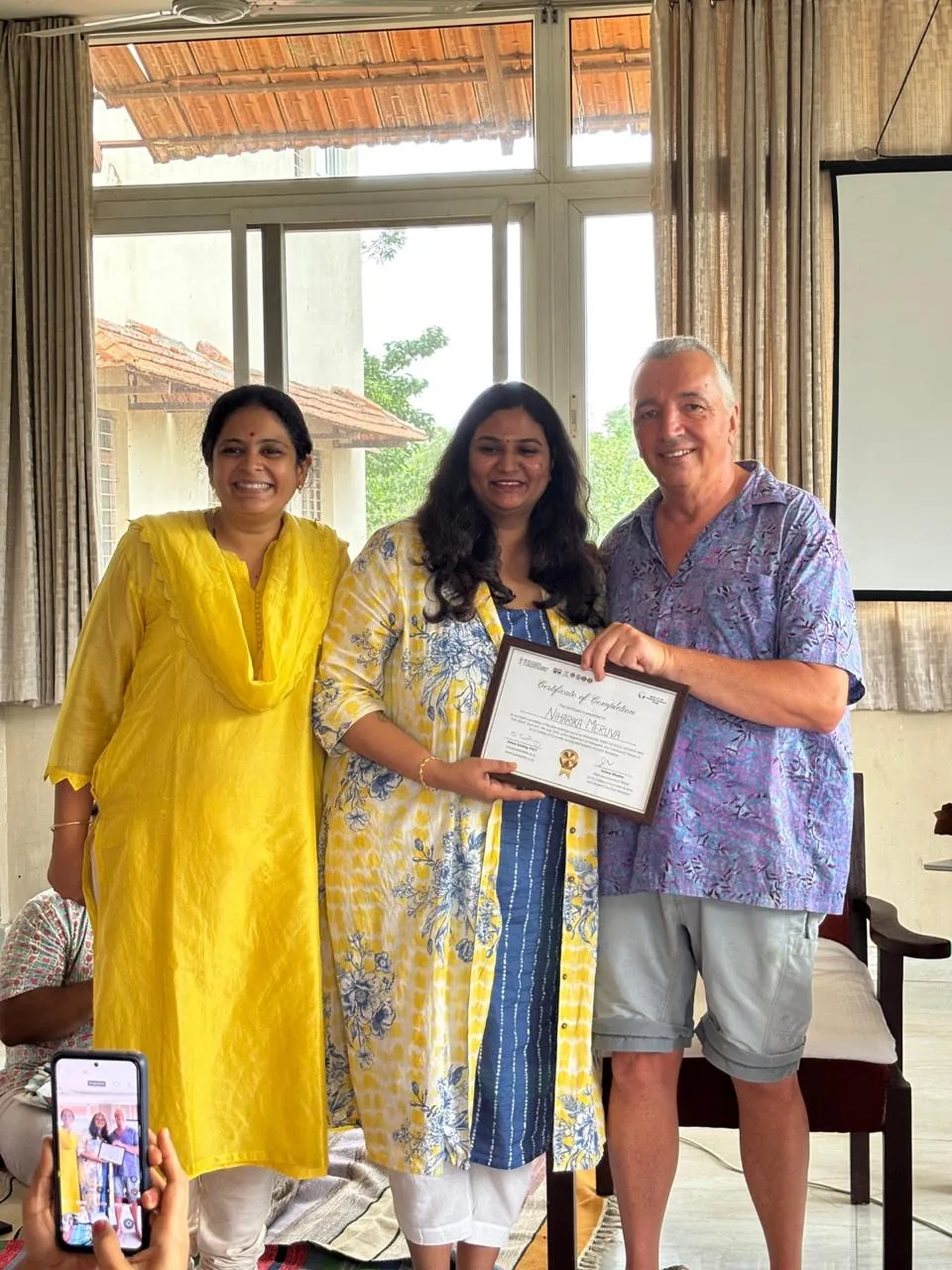 Niharika receiving her course certificate with two of her teachers