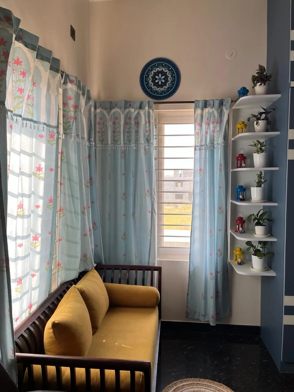 A calm corner of the treatment room with a yellow sofa, floral curtains and shelves of plants