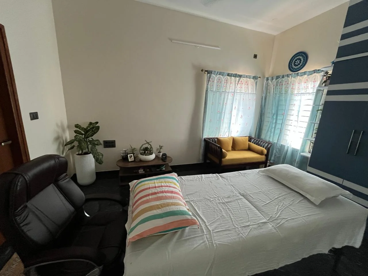 The treatment room at Deha Pragnya Healing Center, with a padded table, yellow sofa and sunlit blue curtains